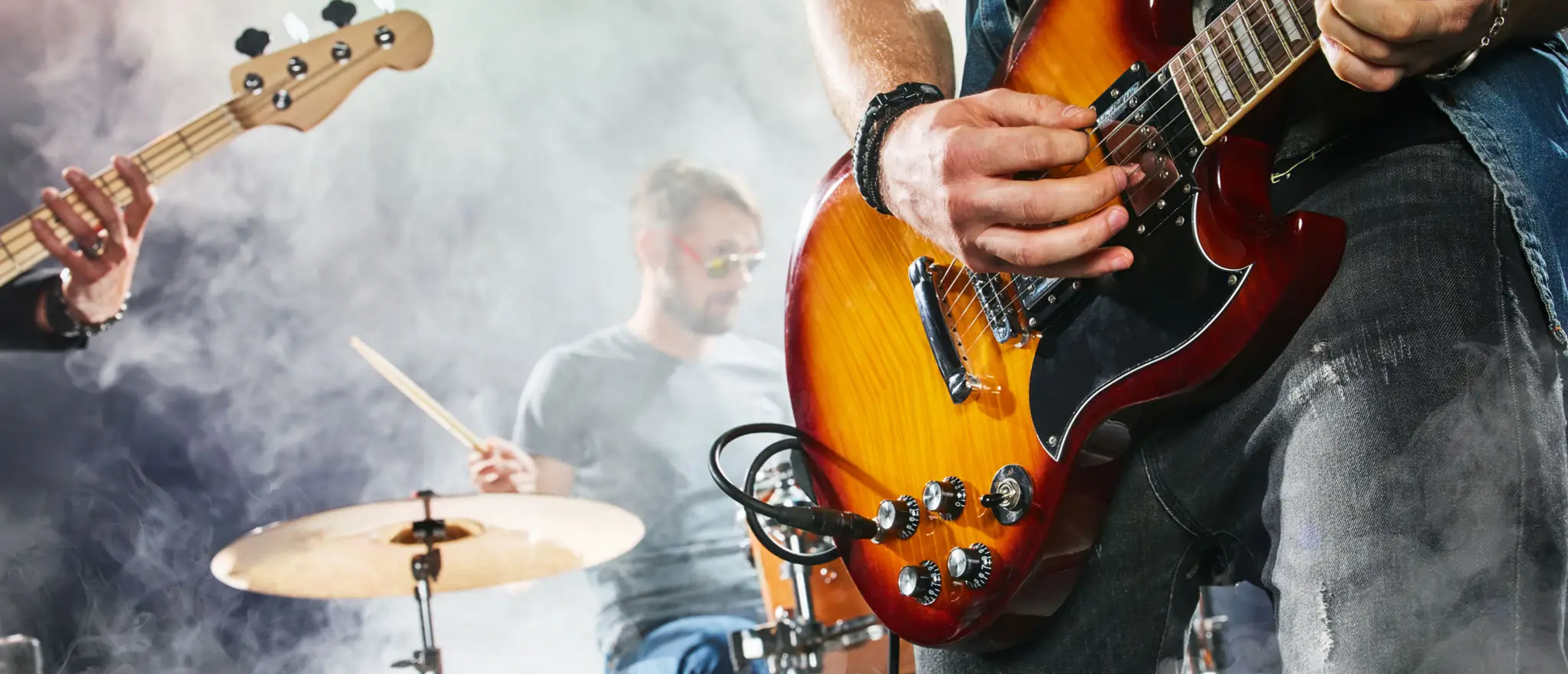 Close-up electric guitarist with drummer on stage