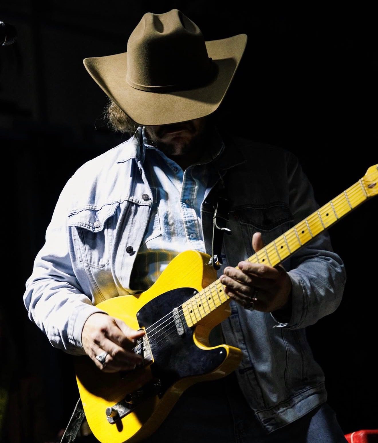 Musician in cowboy hat playing yellow electric guitar