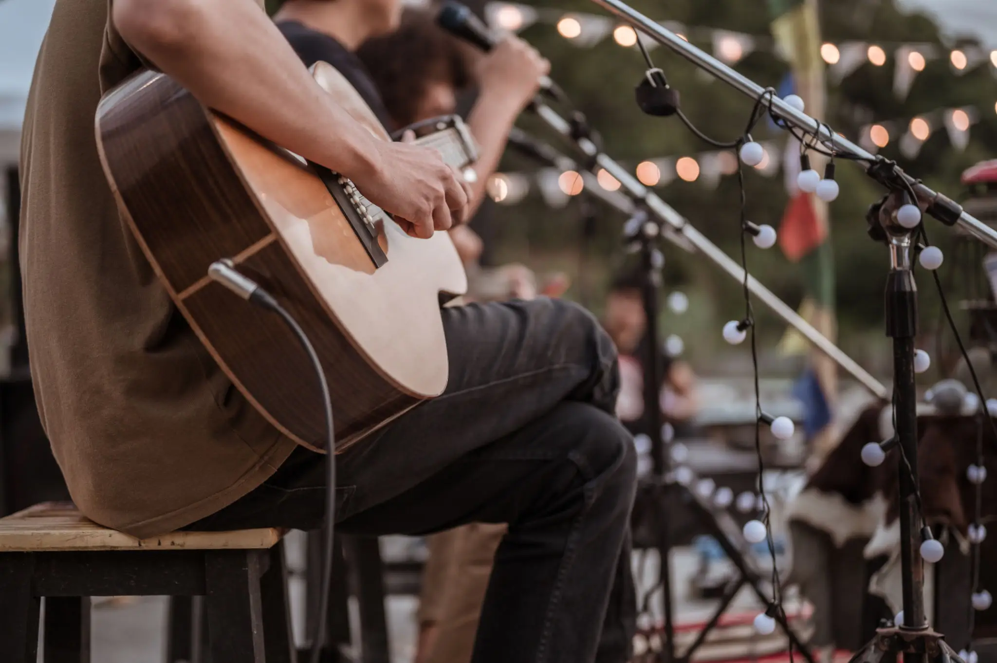 Musician playing acoustic guitar at outdoor concert