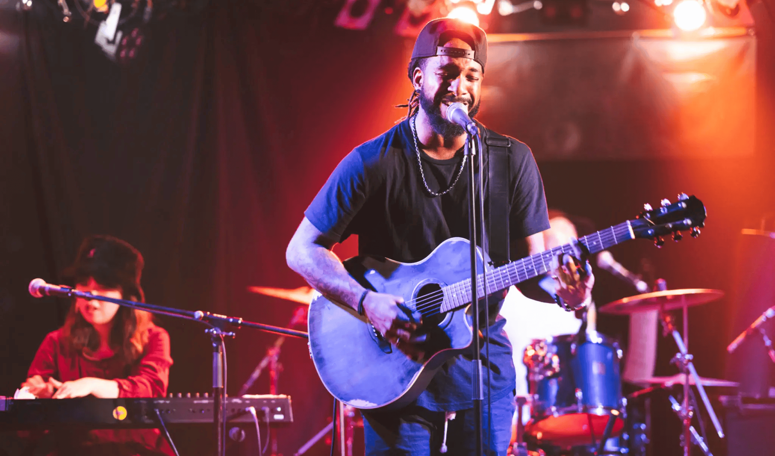 Smiling male singer playing acoustic guitar on stage